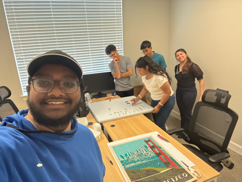 Interns gathered around a desk and whiteboard in the office