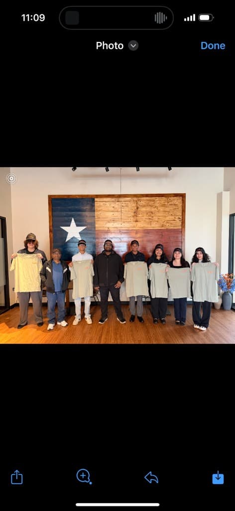 The intern class and Mike lined up under the Texas flag, holding new shirts and caps